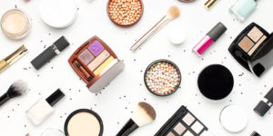 Pattern from Set of decorative cosmetics mascara powder lipstick eyeshadow blush makeup brush, star confetti on light background top view Flat lay.