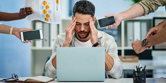 Shot of a young man experiencing a headache at work while being overwhelmed