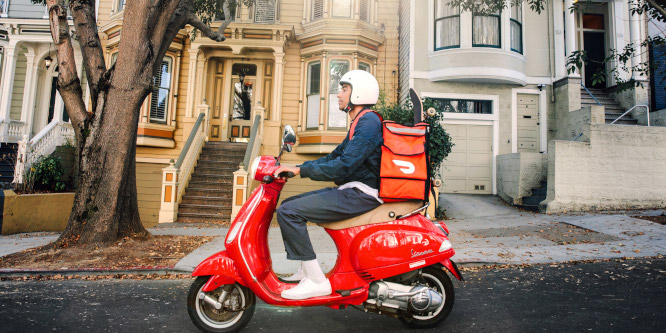 Person wearing a helmet riding a scooter making a DoorDash delivery with a DoorDash branded bag on his back