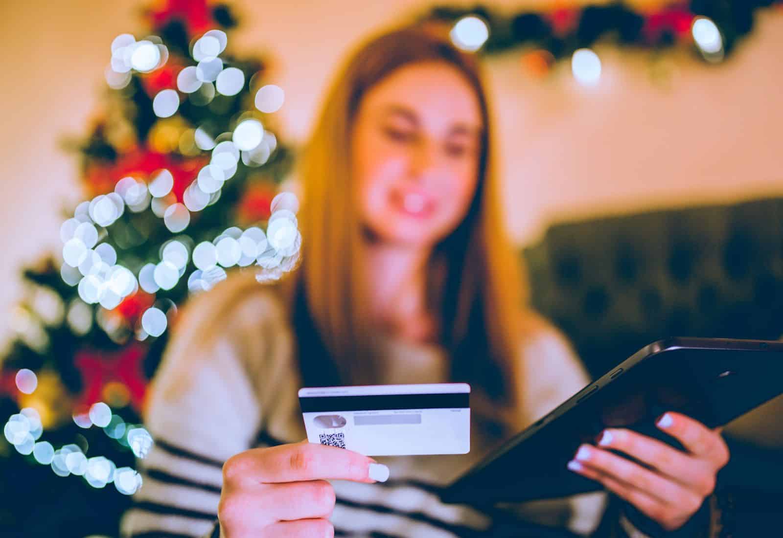 A Gen Z woman is holiday shopping online, credit card in hand.