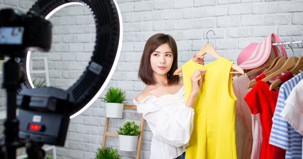 Woman holding up clothes while livestreaming