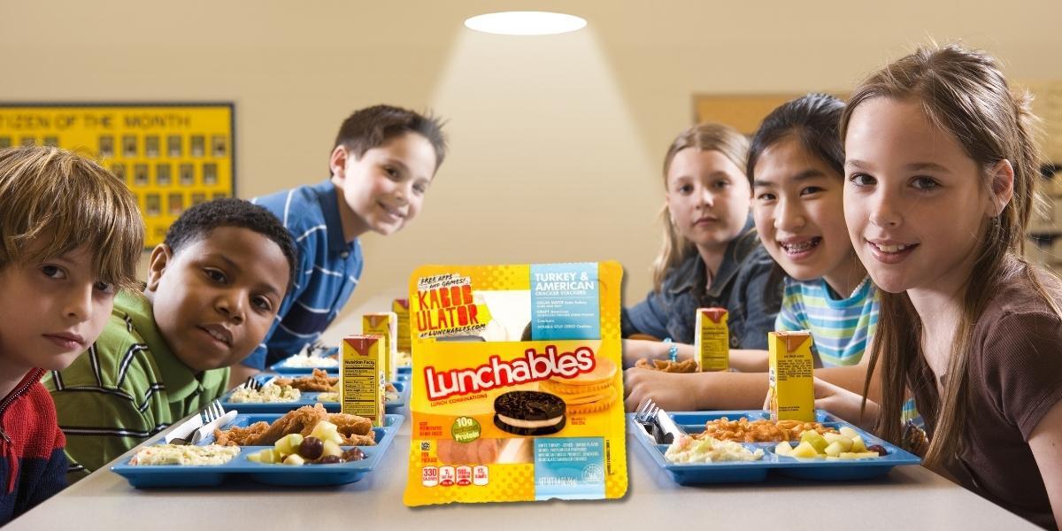 Kids eating school lunch with a Lunchable in the middle of the image