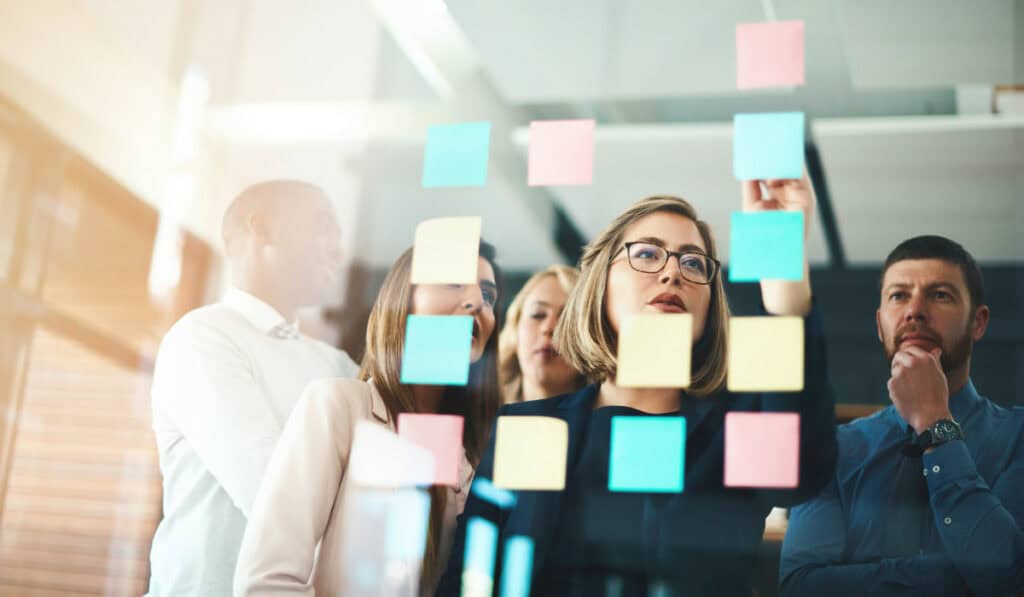 Marketing team thinking of ideas with post-it notes on glass
