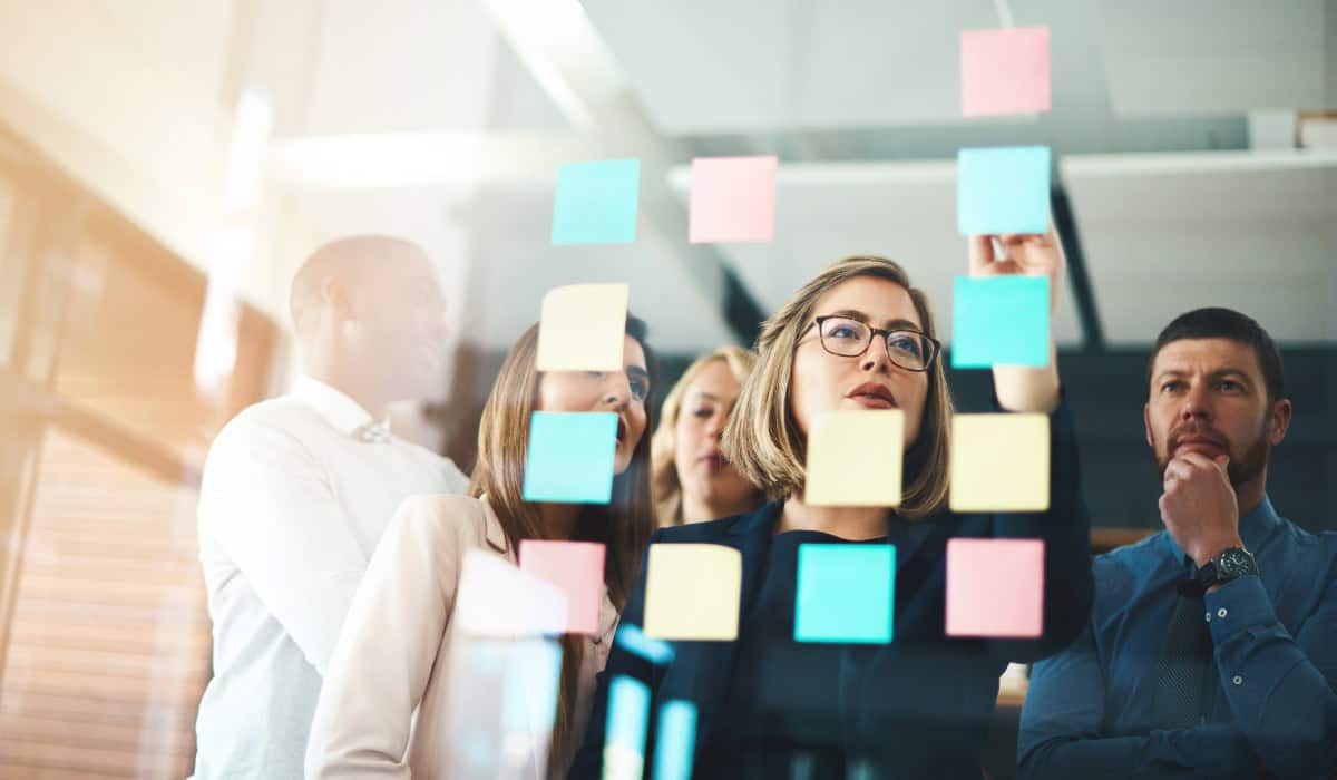 Marketing team thinking of ideas with post-it notes on glass