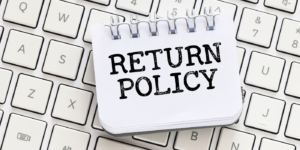The words "Return policy" on a journal on top of a keyboard