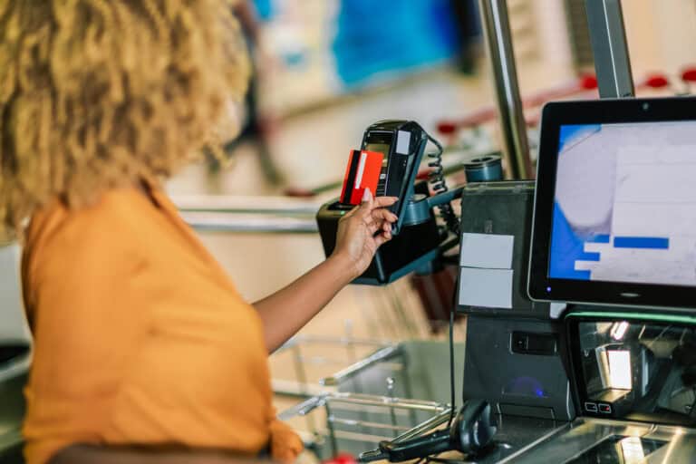 Woman with bank card buying food at grocery store or supermarket self-checkout
