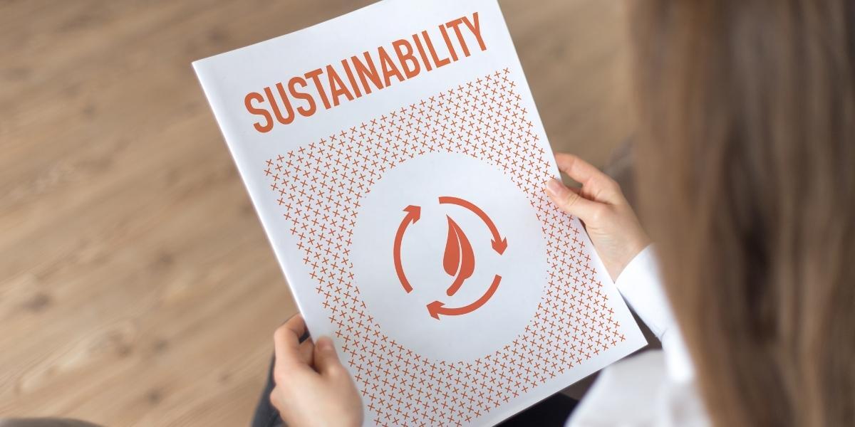 Close-up of a person's hands holding a booklet that says "sustainability"