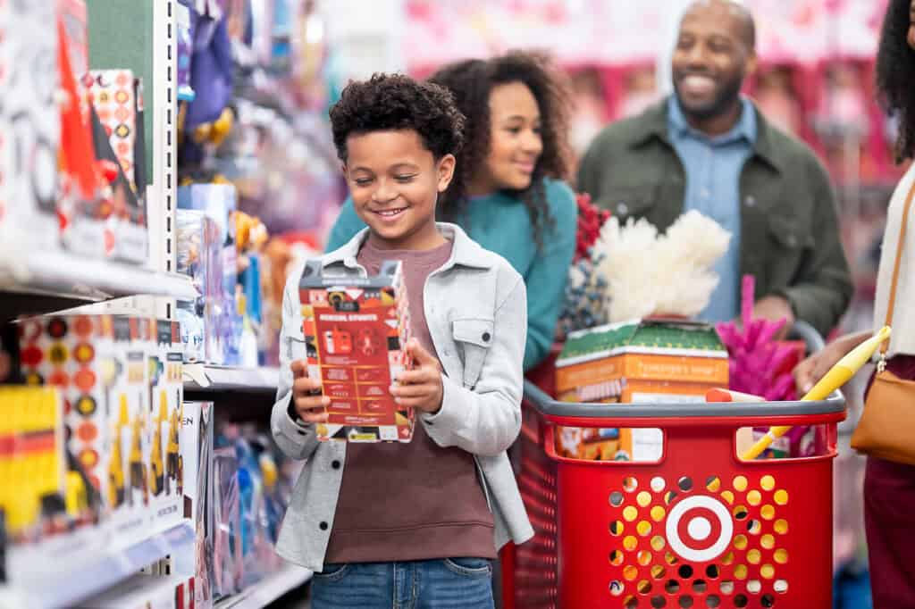 Target holiday shopping. Boy looks at toy as family in background.