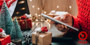 Person on a phone in front of a laptop with Christmas decorations