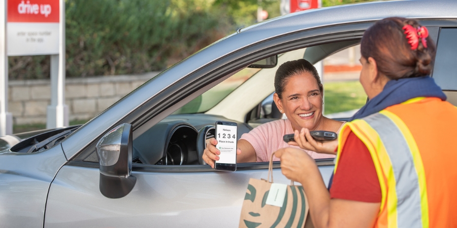 Target employee handling a Starbucks order to a woman in a car