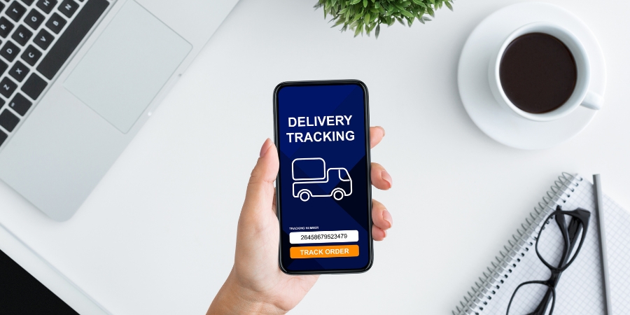Hand holding a phone that says "delivery tracking"