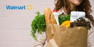 Woman holding bag of groceries next to a Walmart logo