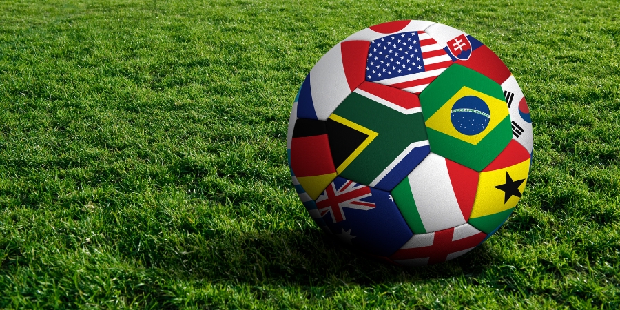 Soccer ball made up of flags from around the world on a green field