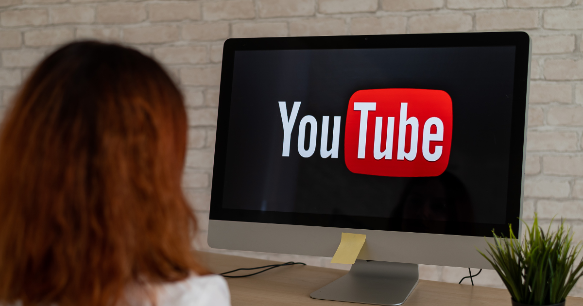Woman looking at a computer screen with the YouTube logo on it