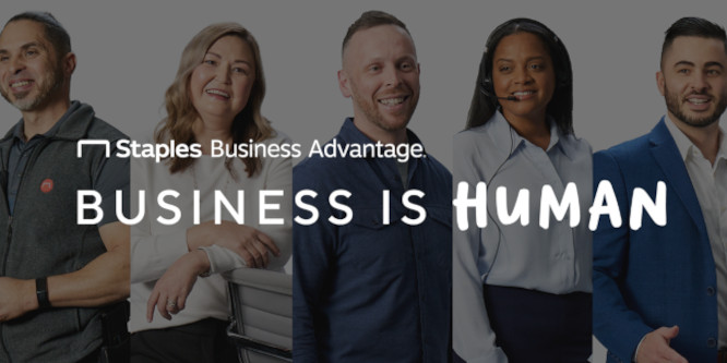 Five people dressed business casual standing and smiling, the backdrop for superimposed text in white reading "Business is Human" with "Staples Business Advantage" in small print above it.