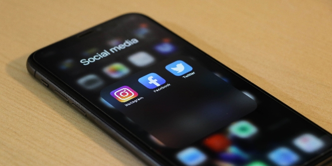 iPhone with "Social Media" folder open to display Instagram, Facebook, and Twitter icons