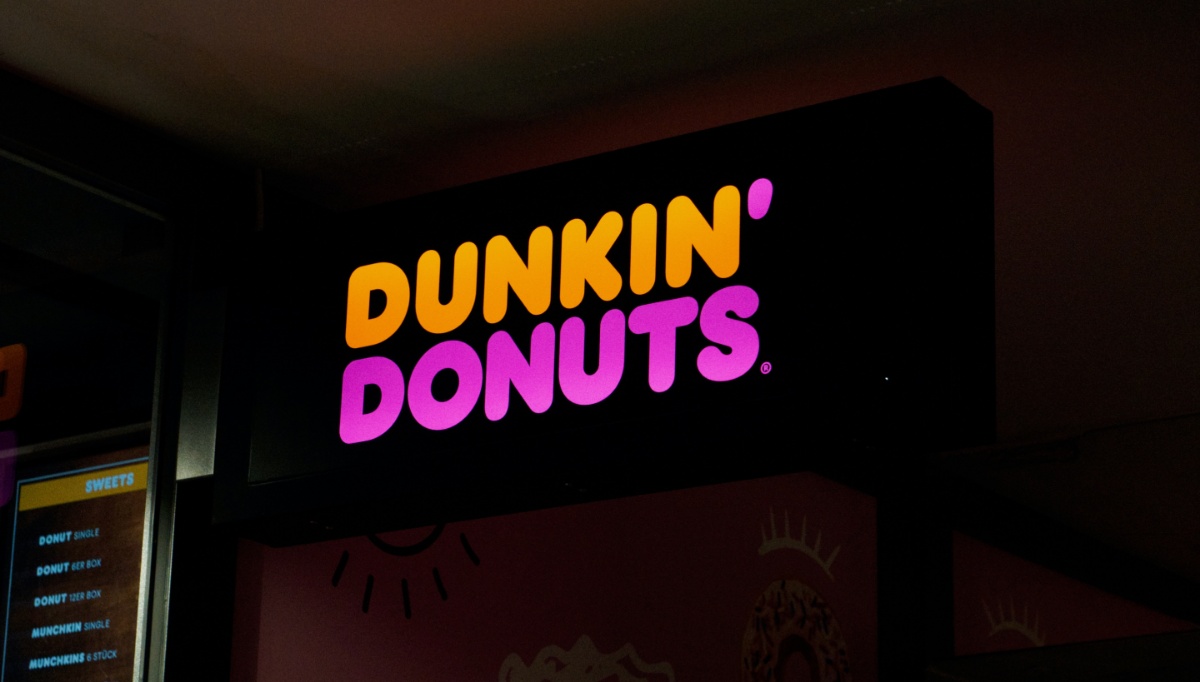 A Dunkin Donuts sign lit up at night.