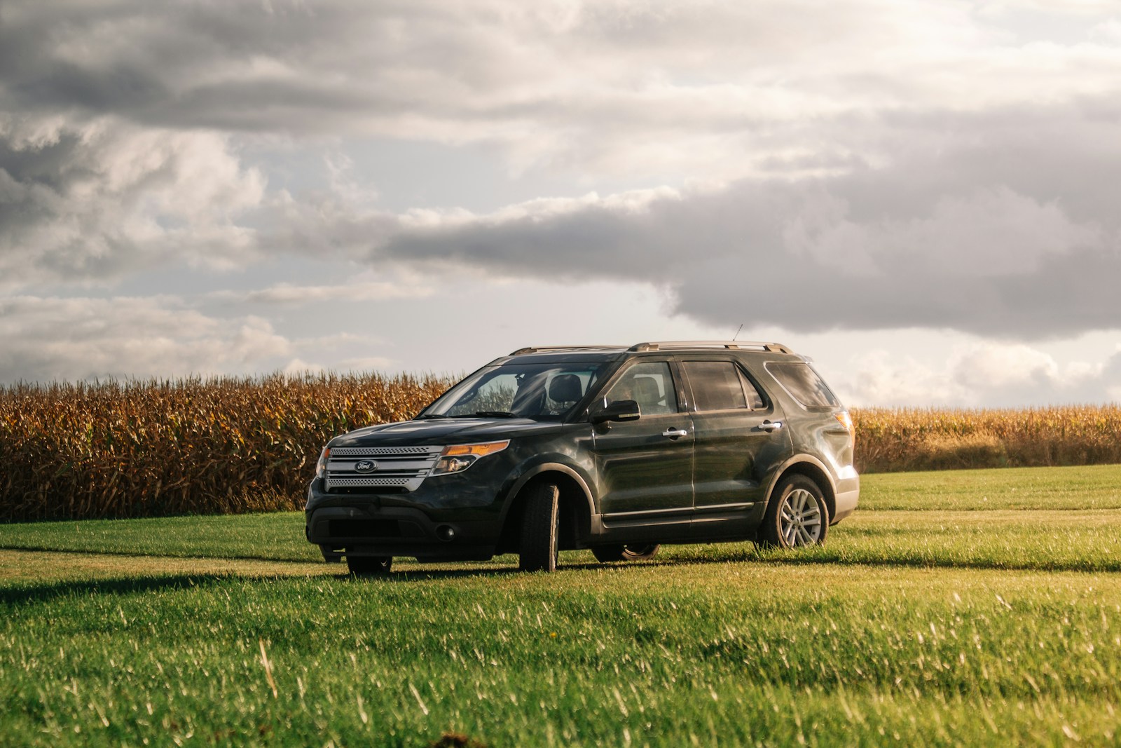 a black ford explorer suv parked in a field of grass