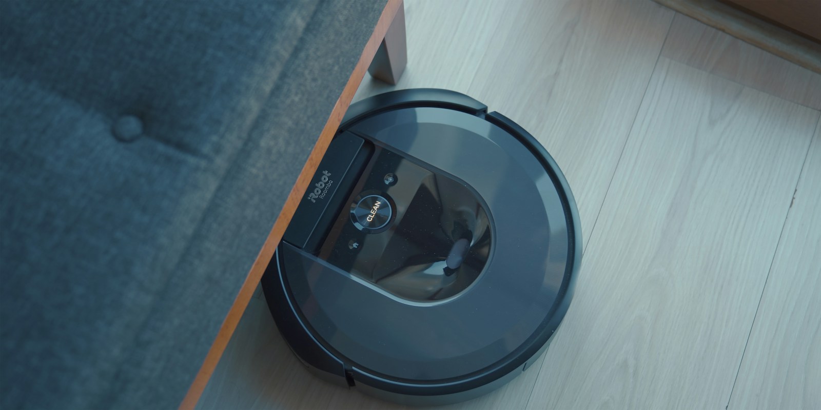 an irobot robotic vacuum is on the floor next to a couch