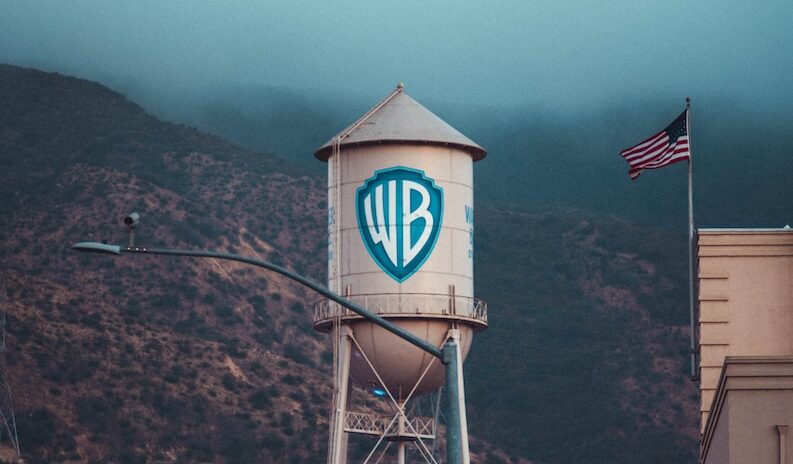 a water tower with a sign on it in front of a mountain warner brothers