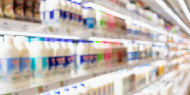Image of a dairy cooler taken at an angle, blurred, milk containers lining the three visible shelves
