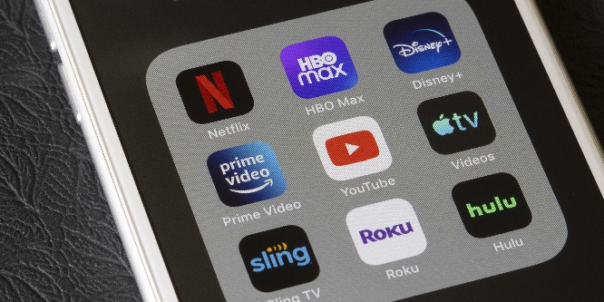 Assorted streaming apps are seen on an iPhone, including Netflix, HBO Max, Disney Plus, Amazon Prime Video, YouTube, Apple TV, Sling TV, Roku, and Hulu.