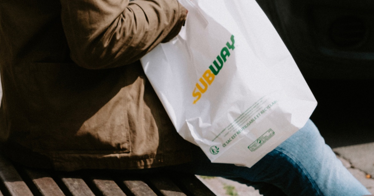 A customer with a Subway sandwich takeout bag.