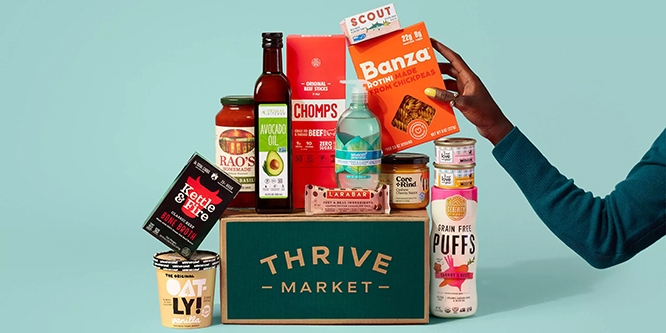 Person touching a stack of grocery items sitting on top of a Thrive Market box