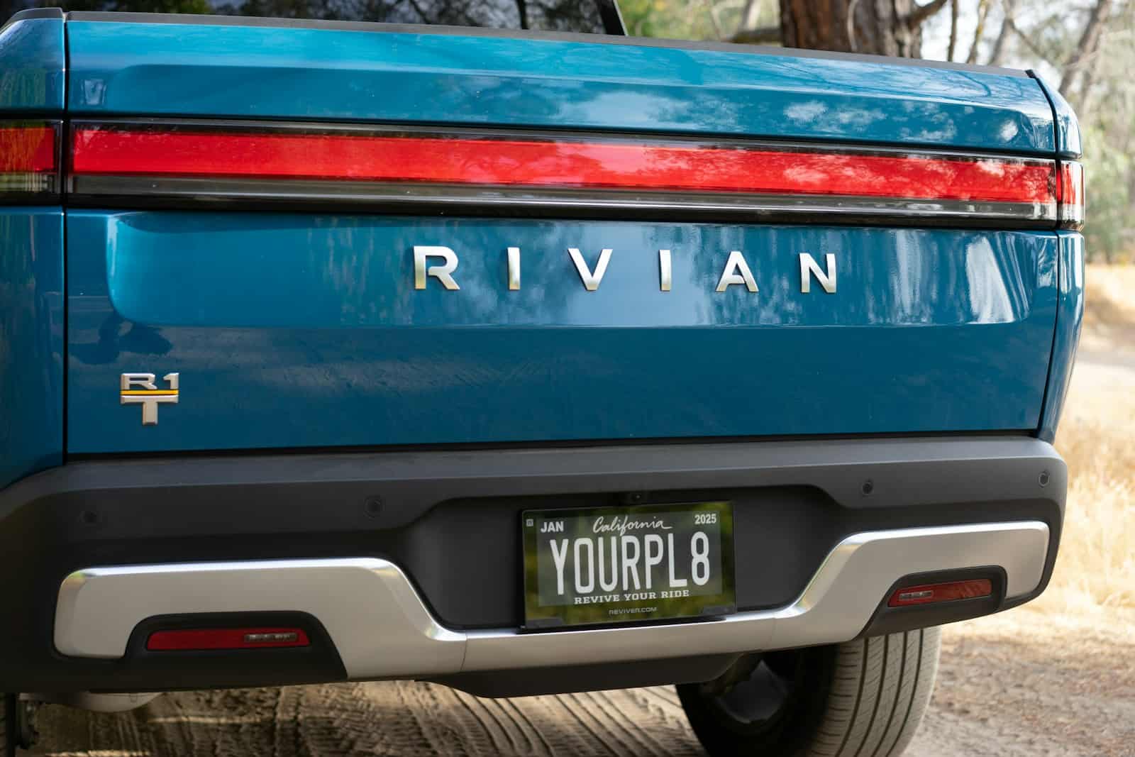 rivian the back end of a blue car with a license plate