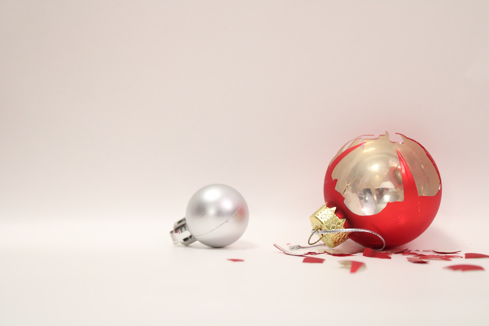 a red and silver christmas ornament next to a silver ornament symbolizing holiday layoffs